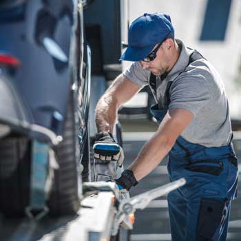 Soccorritore-stradale-che-fissa-auto-sul-carro-attrezzi-con-cinghie-a-cricchetto